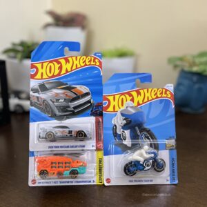 Hot Wheels Pack of 3 featuring ’20 Ford Mustang Shelby GT500, 1966 Triumph Tiger 100, and HW Ultimate T-Rex Transporter. Authentic 1:64 scale diecast models – available at The Miniature Hub.